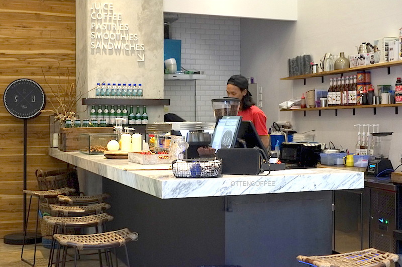 Barista sedang beraksi di balik coffee bar.