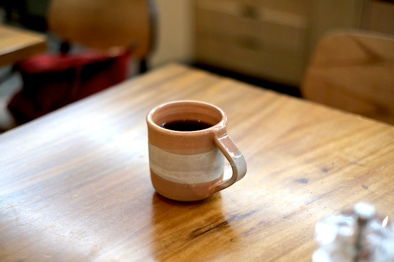 Cangkir cantik memeluk mesra kopi nikmat.